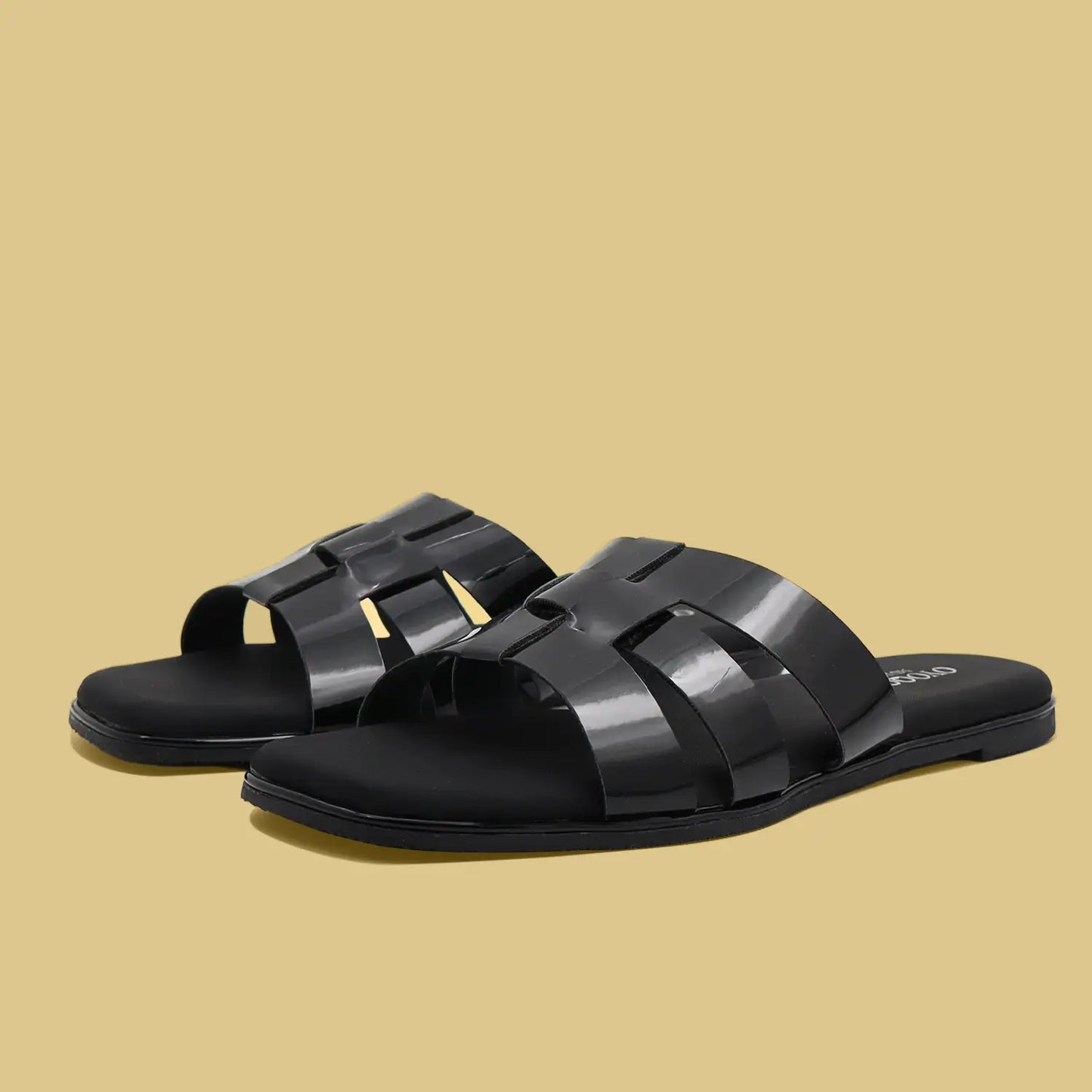 Black flat sandals with woven straps on a beige background