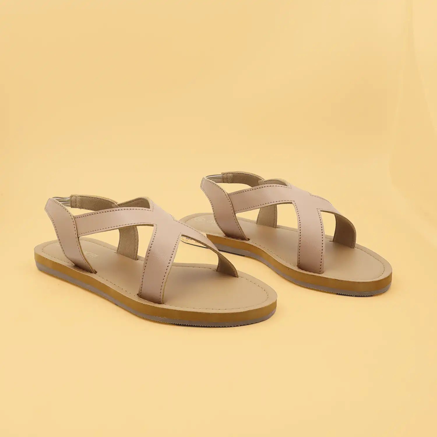 A pair of women's minimalist flat sandals with crisscrossing straps and a tan sole