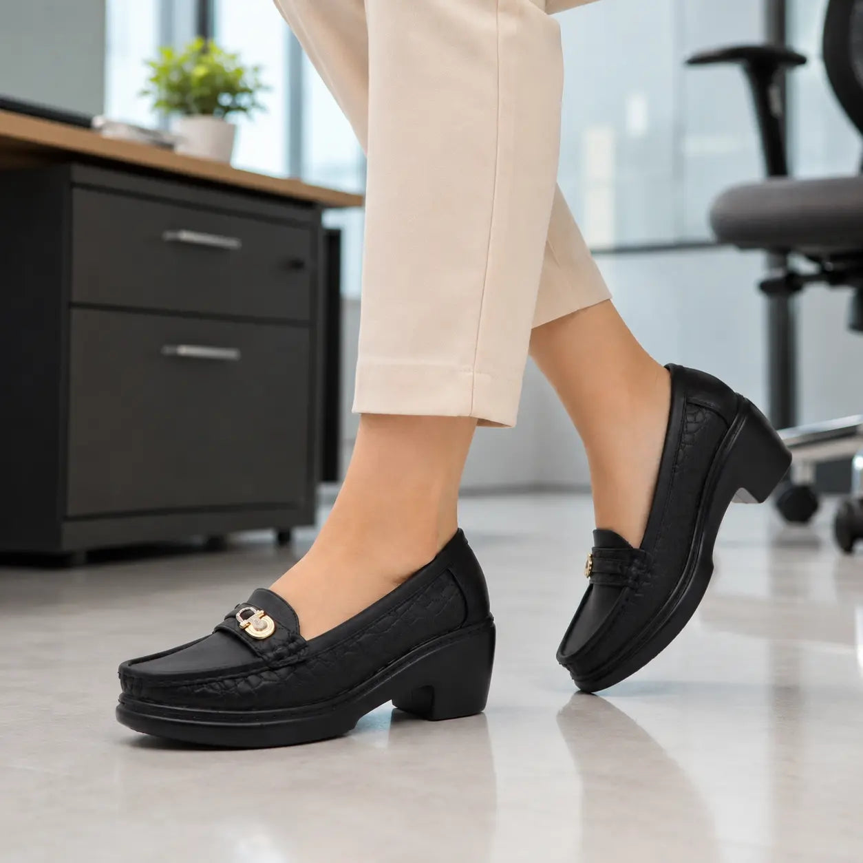 Person wearing block black loafers in an office setting