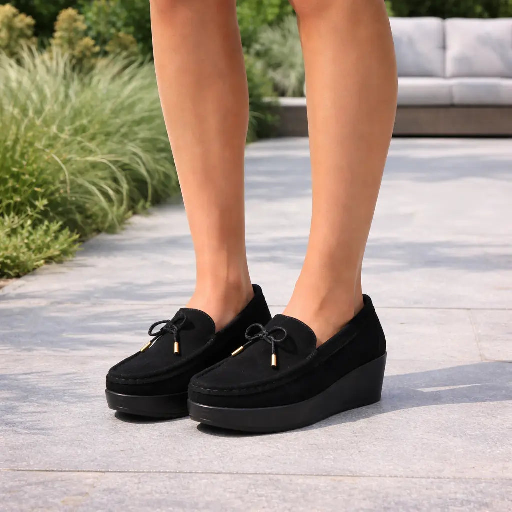 Lifestyle view of women's black wedge heel loafers