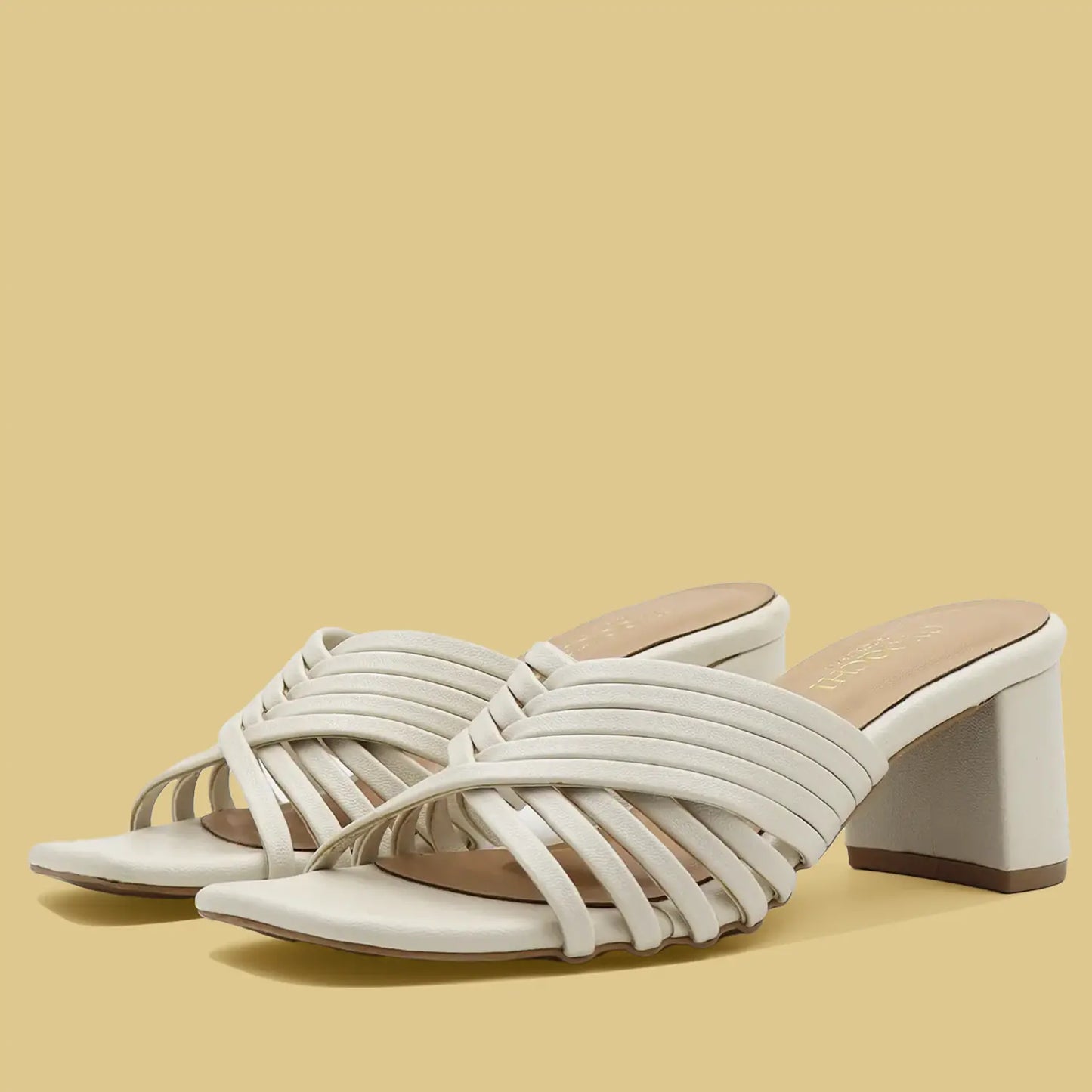 White strappy sandals with a block heel on a beige background