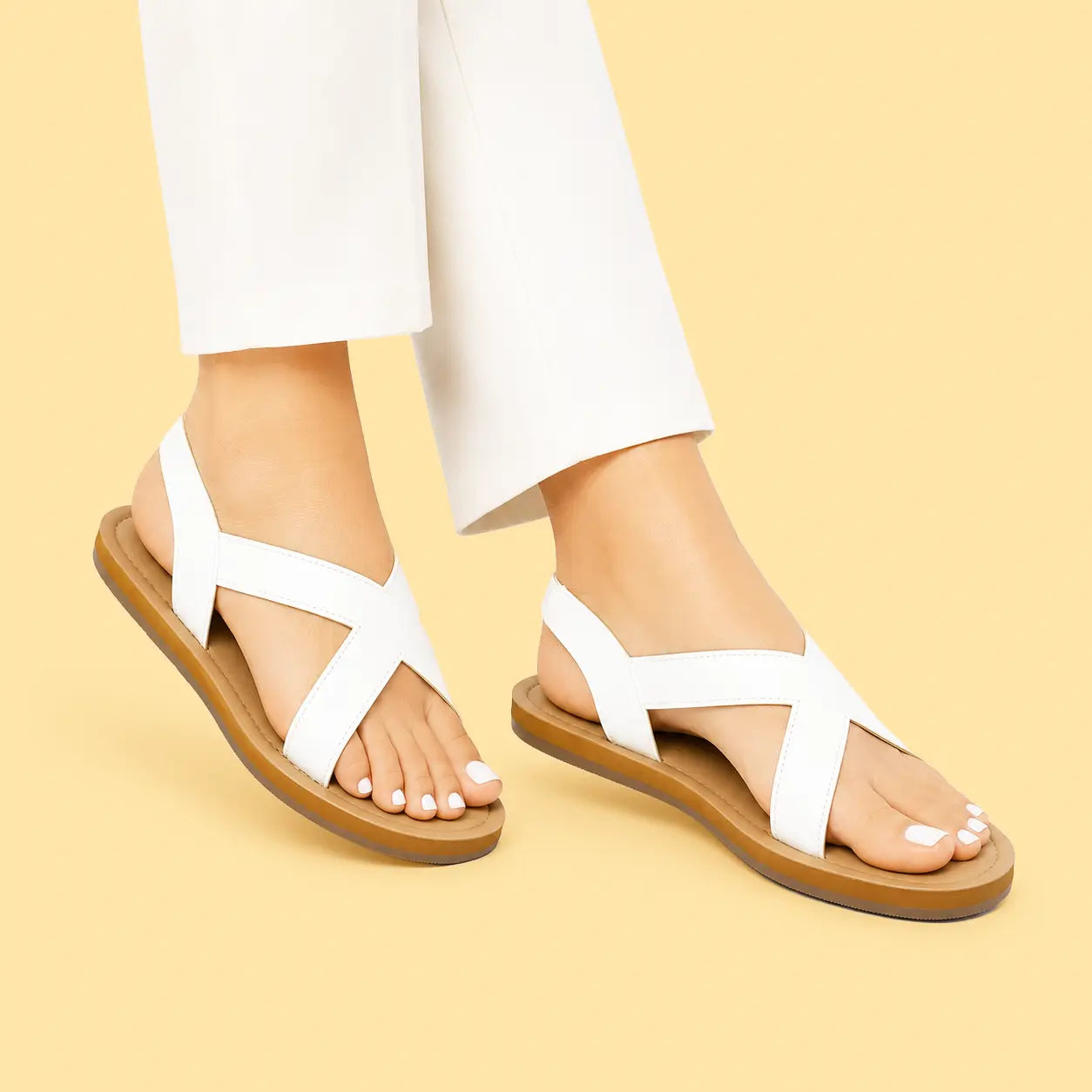 Women's white criss-cross flat sandals with a browen sol, shown on a model's feet