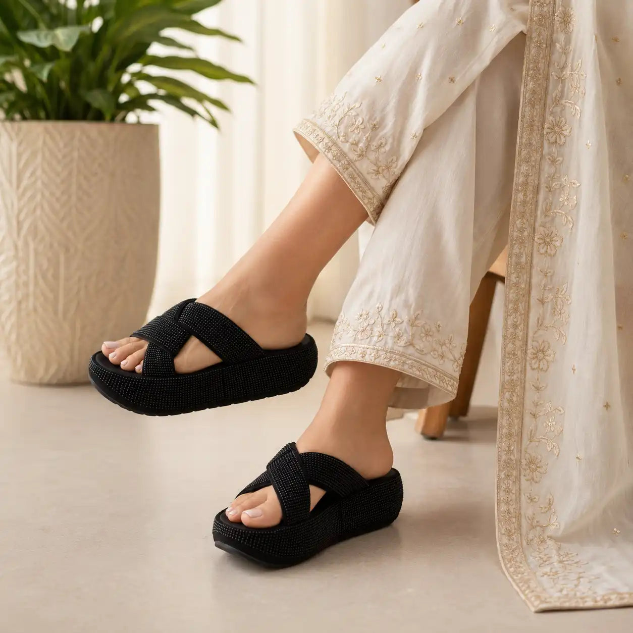 A person wearing black woven caged slide sandals with thick black platform soles