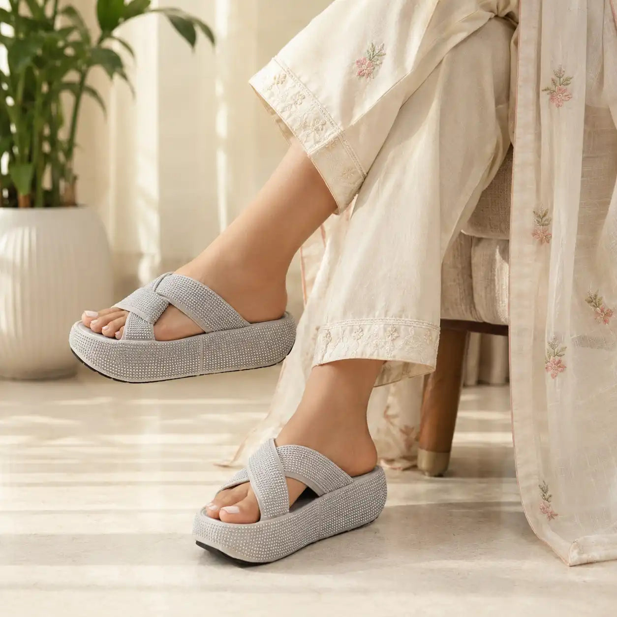 A person wearing  silver woven platform slide sandals with wide crisscross straps
